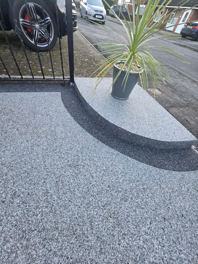 Silver resin driveway with a curved charcoal border around a planter