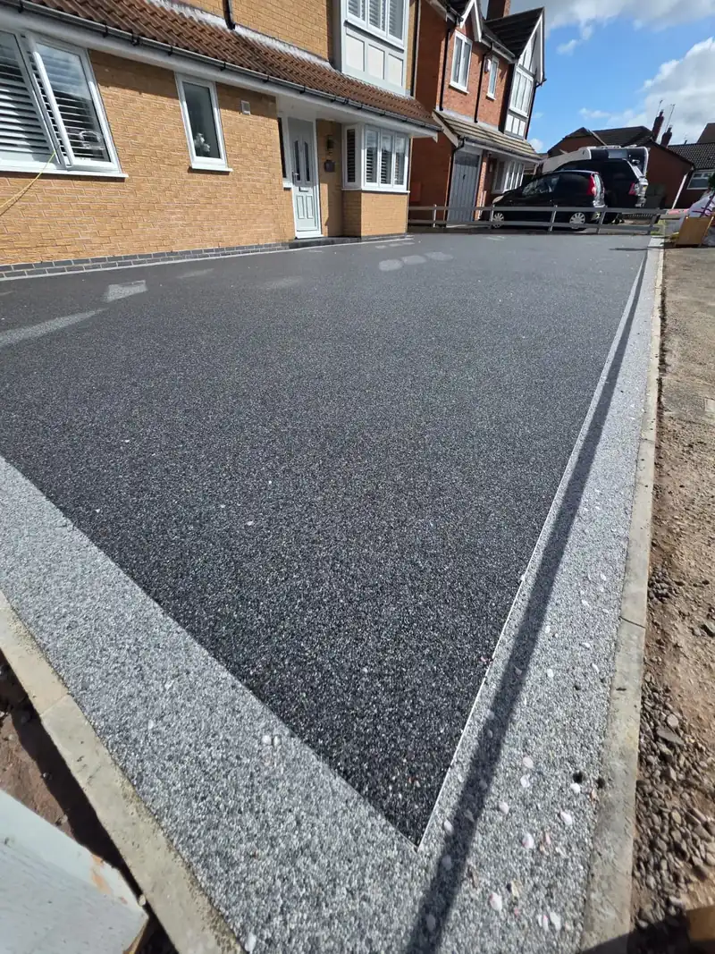 Crisp edge detail where a charcoal resin driveway meets the boundary