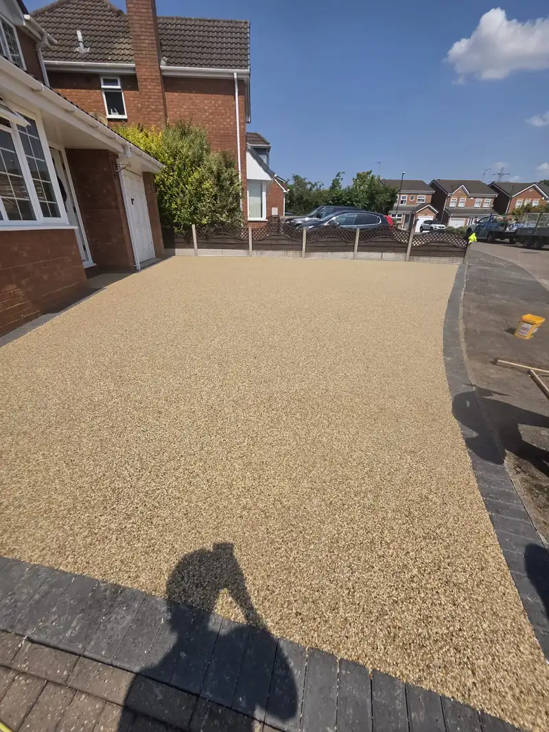 Wide gold-toned resin bound driveway running up to a detached brick house