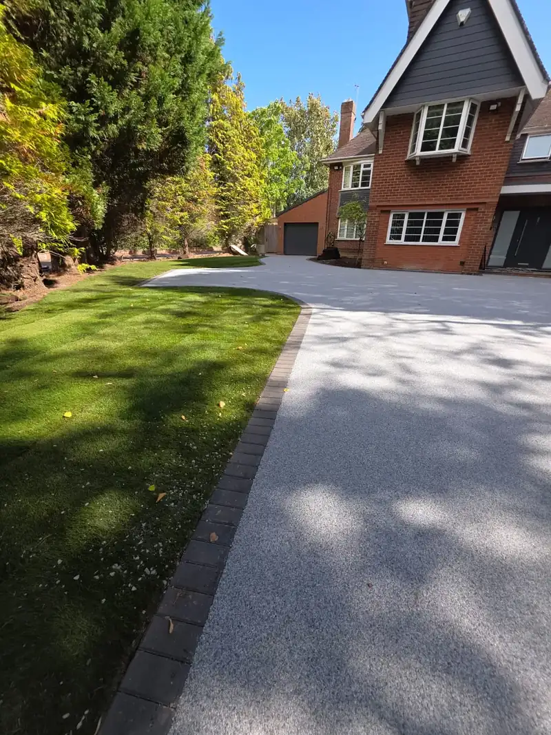Pale silver resin driveway running alongside a striped lawn